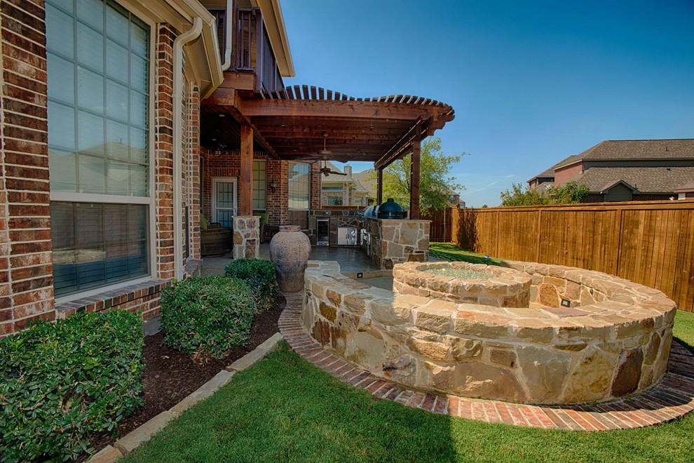 This is an example of a medium sized rustic back patio in Dallas with a fire feature, concrete slabs and a pergola.