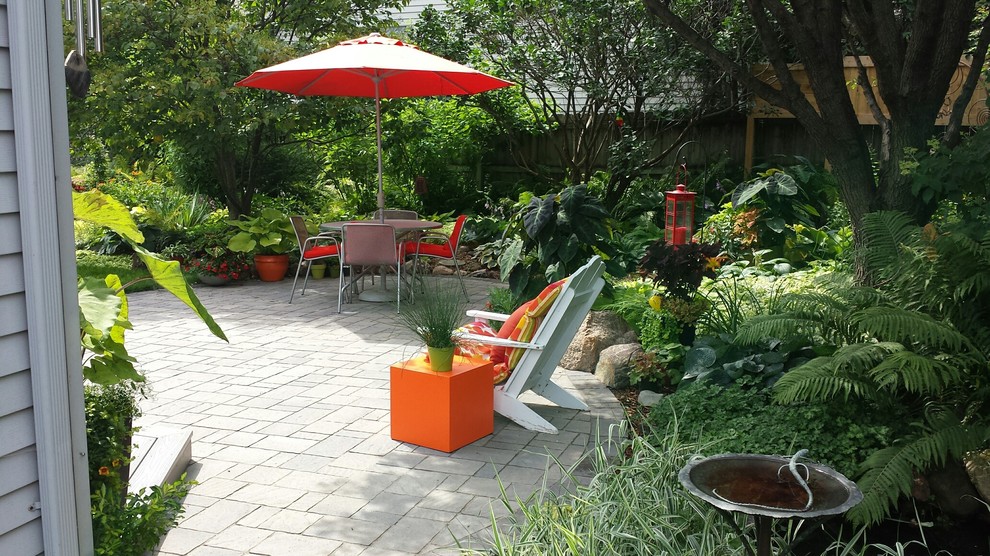 Imagen de patio actual de tamaño medio sin cubierta en patio trasero con adoquines de hormigón