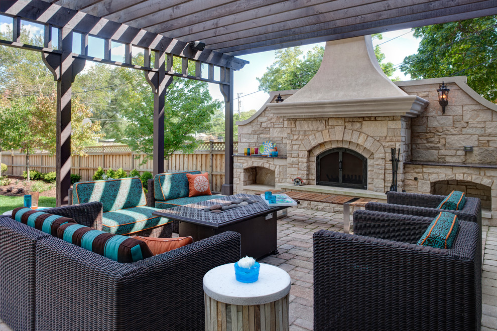 Réalisation d'une grande terrasse arrière design avec des pavés en béton, une pergola et une cheminée.