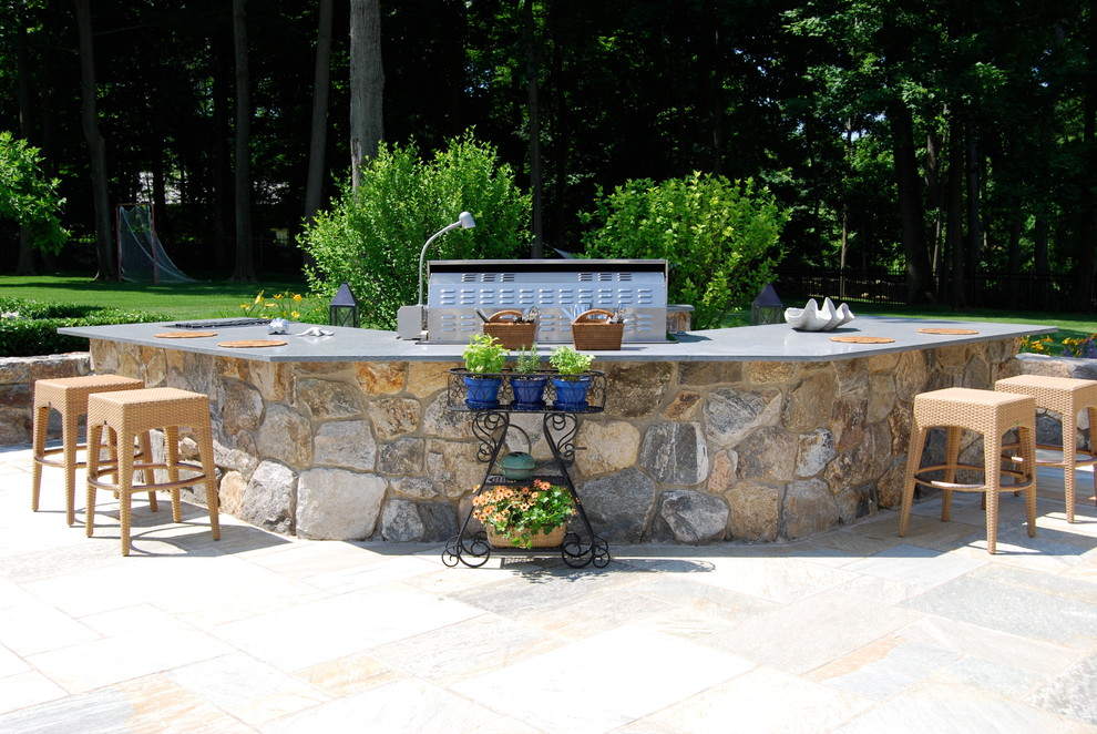 Cette image montre une terrasse arrière traditionnelle de taille moyenne avec une cuisine d'été, des pavés en pierre naturelle et aucune couverture.