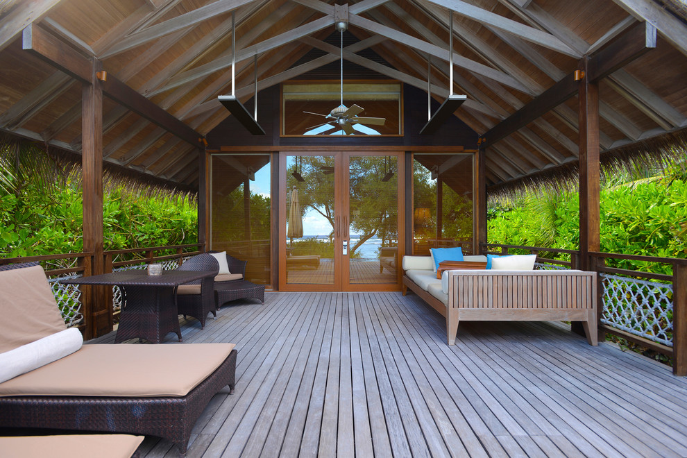 Idee per un patio o portico tropicale di medie dimensioni con pedane e un tetto a sbalzo