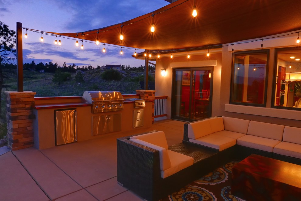 Aménagement d'une grande terrasse arrière éclectique avec une cuisine d'été, des pavés en béton et un auvent.