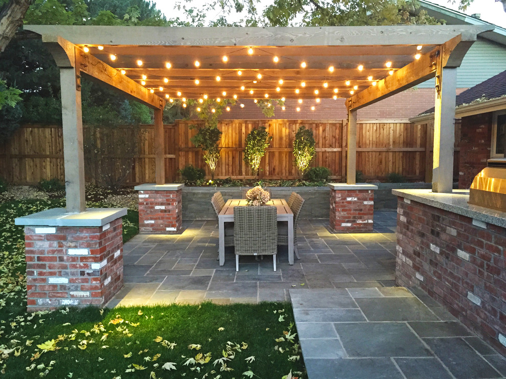 Ejemplo de patio clásico de tamaño medio en patio trasero con adoquines de piedra natural y pérgola