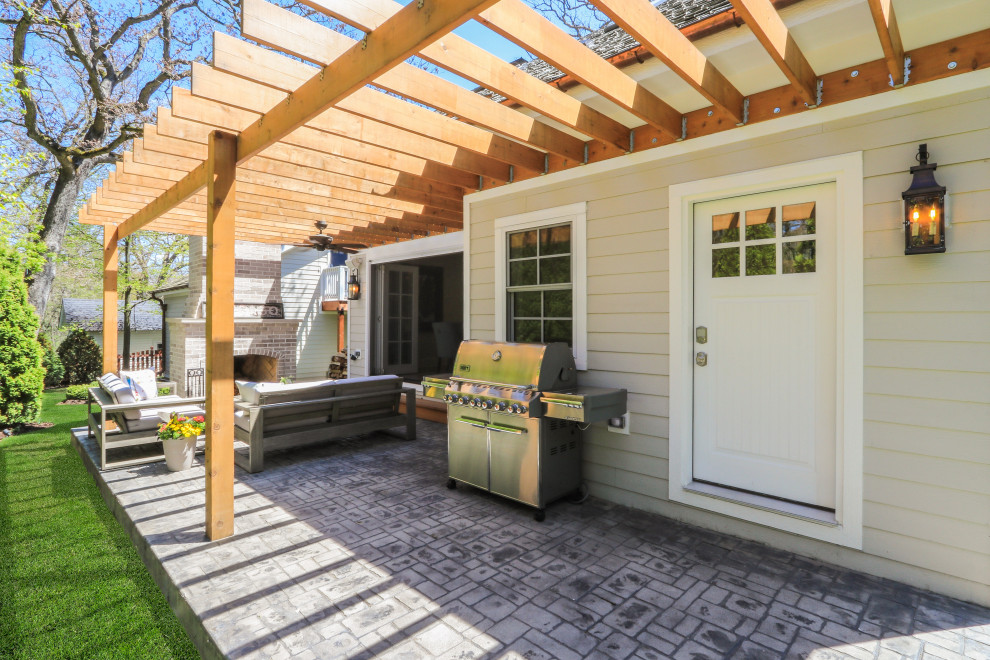 Foto di un patio o portico country di medie dimensioni e dietro casa con un caminetto, cemento stampato e una pergola