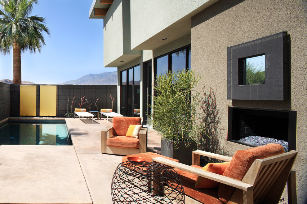 This is an example of a large contemporary back patio in Los Angeles with a fire feature, concrete slabs and no cover.