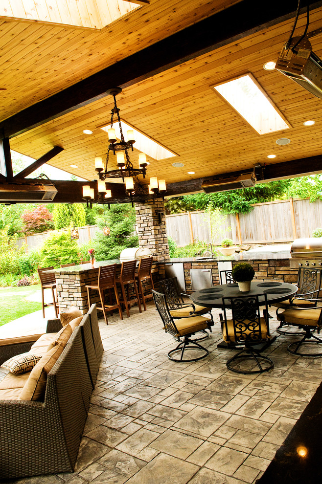 Esempio di un patio o portico tradizionale di medie dimensioni e dietro casa con un focolare, cemento stampato e un tetto a sbalzo