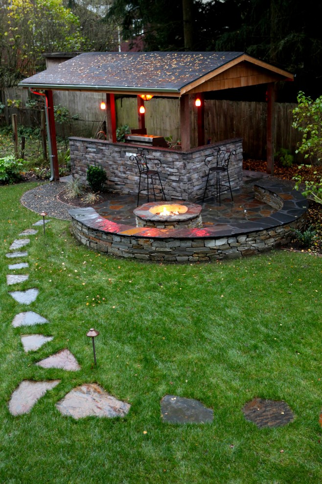 Ejemplo de patio clásico grande en patio trasero con adoquines de piedra natural y cenador