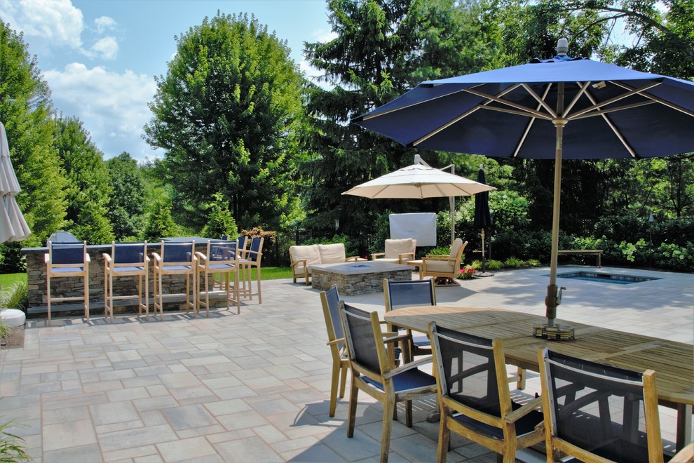 Exemple d'une grande terrasse arrière tendance avec une cuisine d'été, des pavés en pierre naturelle et aucune couverture.