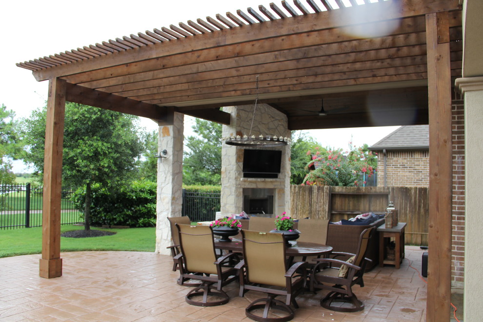 Patio - large traditional backyard stamped concrete patio idea in Houston with a fire pit and a roof extension