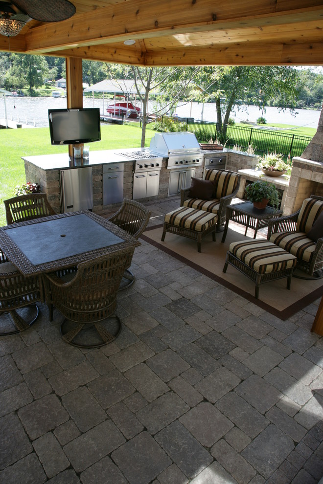 Foto di un patio o portico tropicale di medie dimensioni e dietro casa con un caminetto, pavimentazioni in mattoni e una pergola