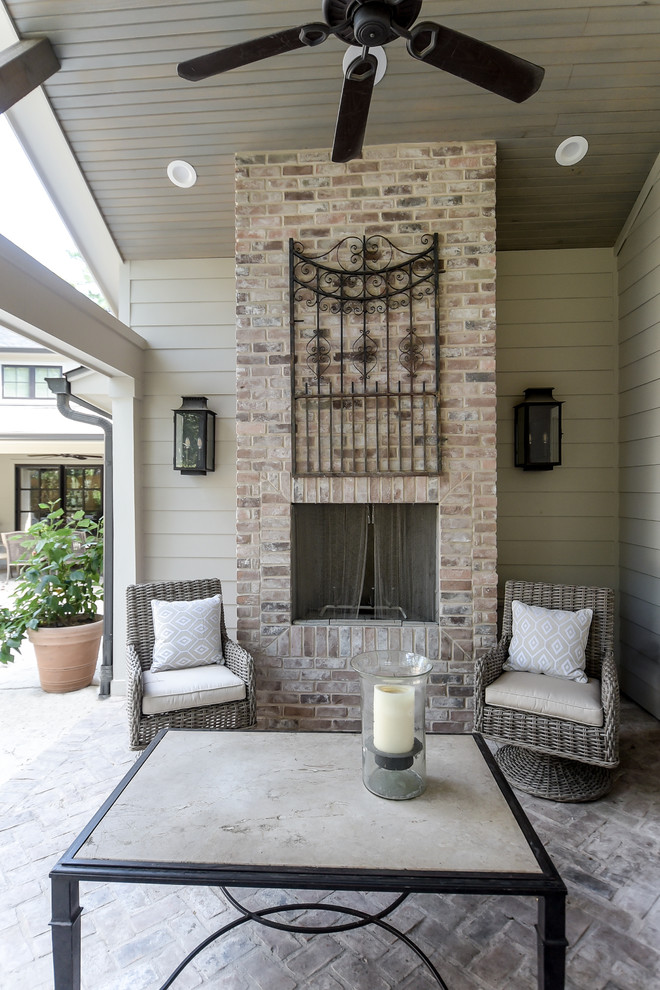 Traditional back patio in Houston with a fireplace, brick paving and a roof extension.