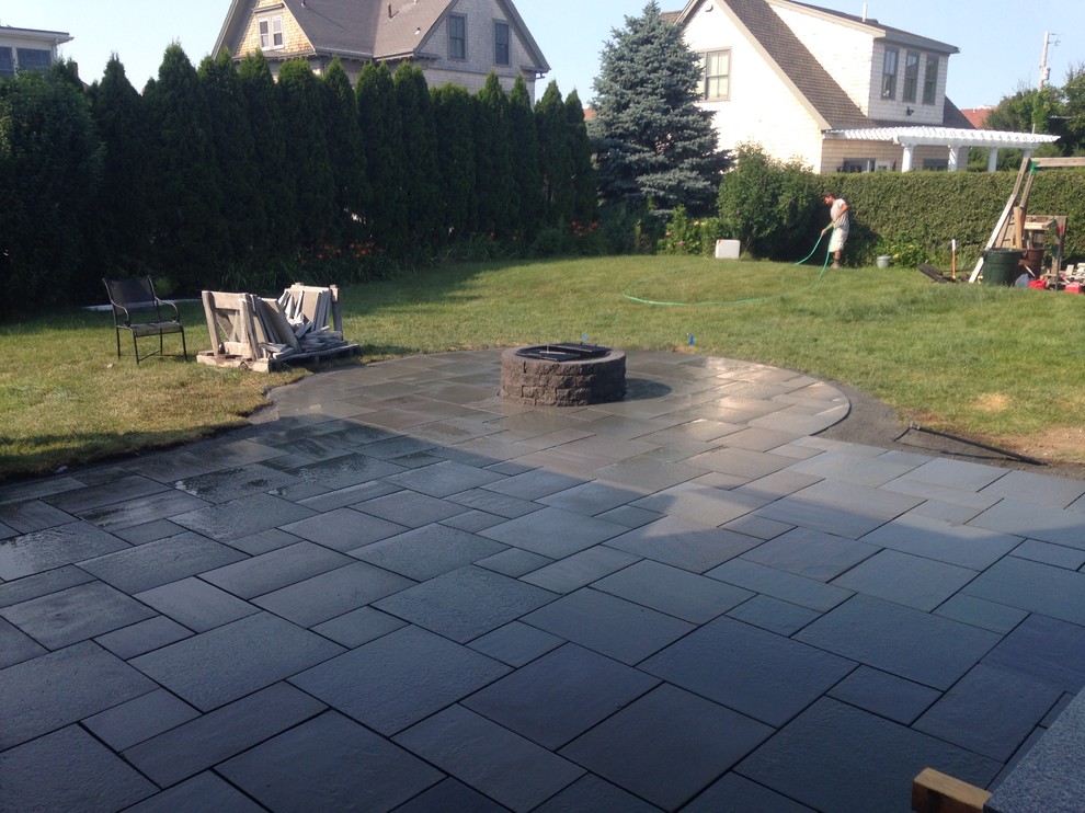 Example of a mid-sized trendy side yard stone patio design in Boston with a fire pit
