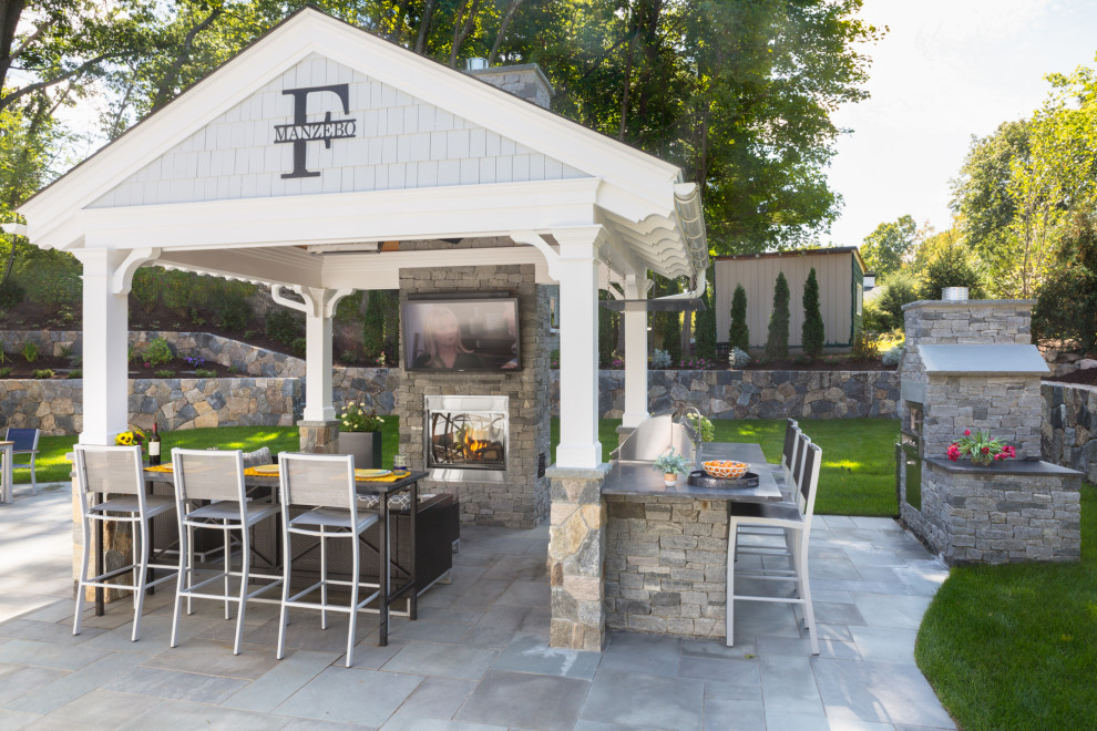 Large classic back patio in Boston with an outdoor kitchen, natural stone paving and a gazebo.