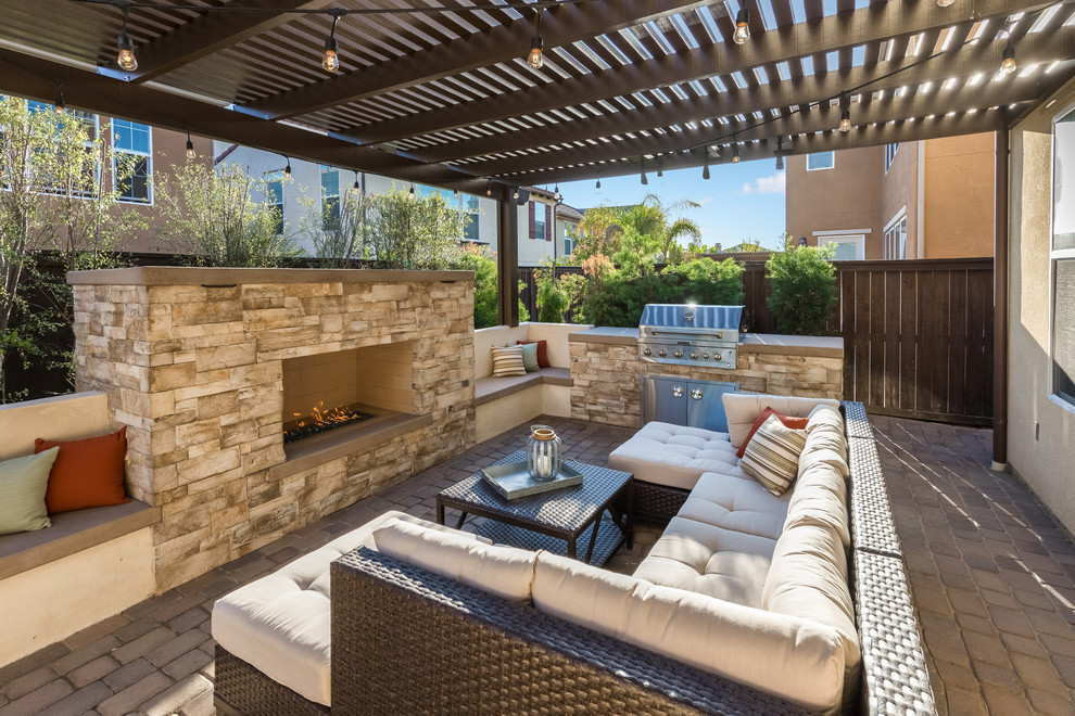 Example of a large transitional backyard concrete paver patio design in Orange County with a fire pit and a pergola
