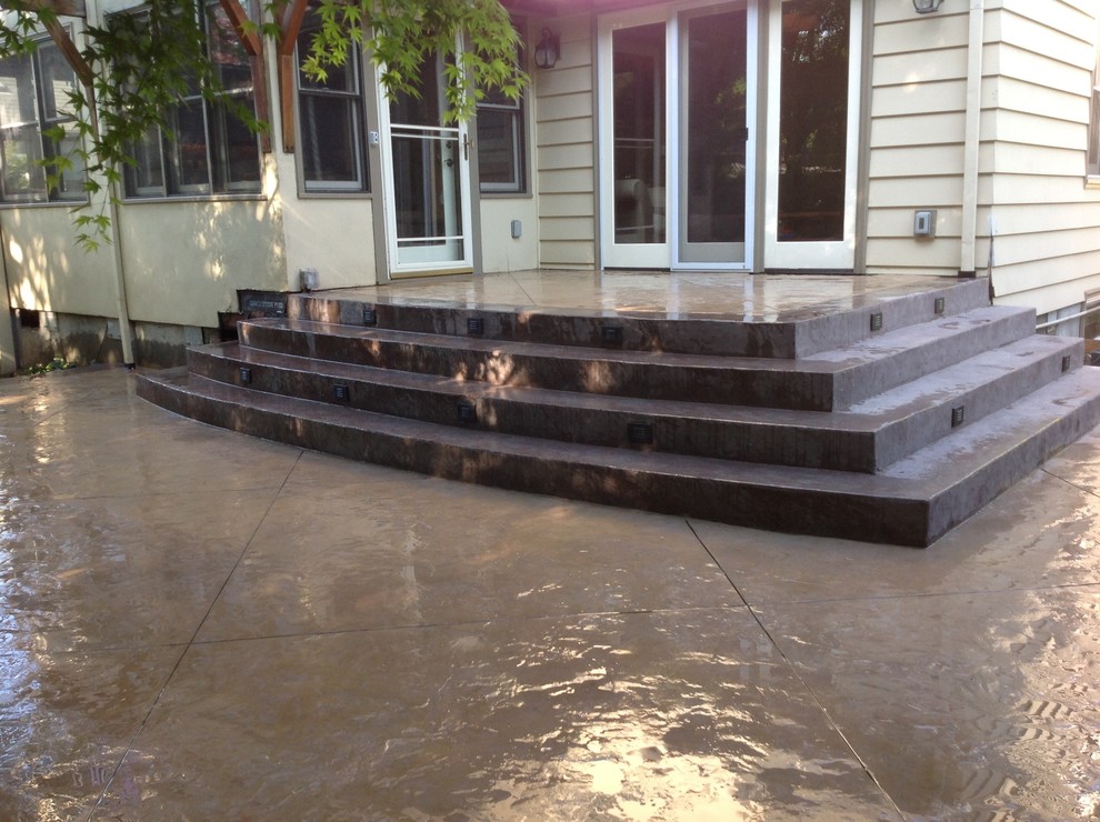 This is an example of a medium sized modern back patio in Portland with concrete slabs and no cover.
