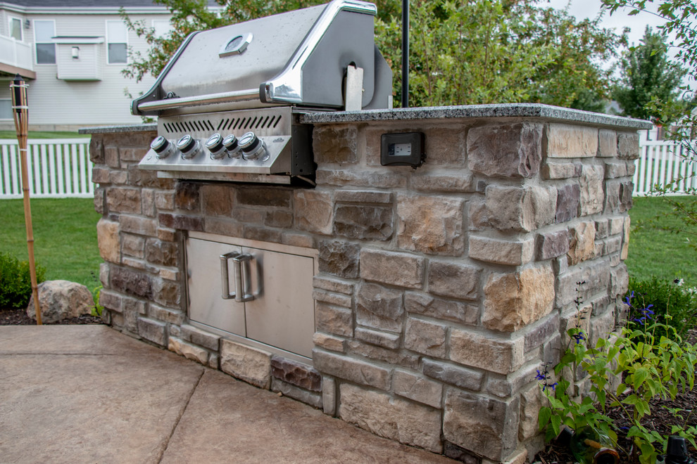 Immagine di un patio o portico di medie dimensioni e dietro casa con un caminetto, cemento stampato e un tetto a sbalzo