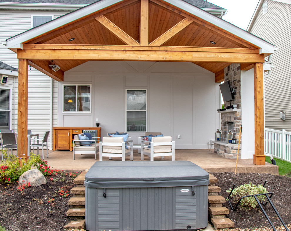 Immagine di un patio o portico di medie dimensioni e dietro casa con un caminetto, cemento stampato e un tetto a sbalzo