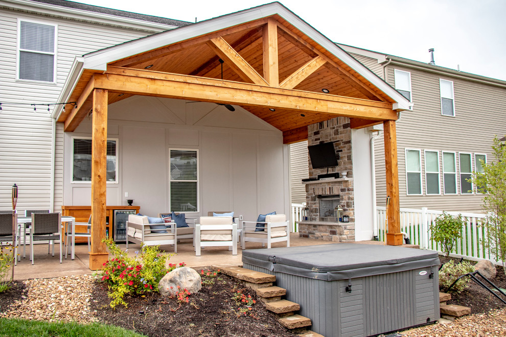 Idee per un patio o portico di medie dimensioni e dietro casa con un caminetto, cemento stampato e un tetto a sbalzo