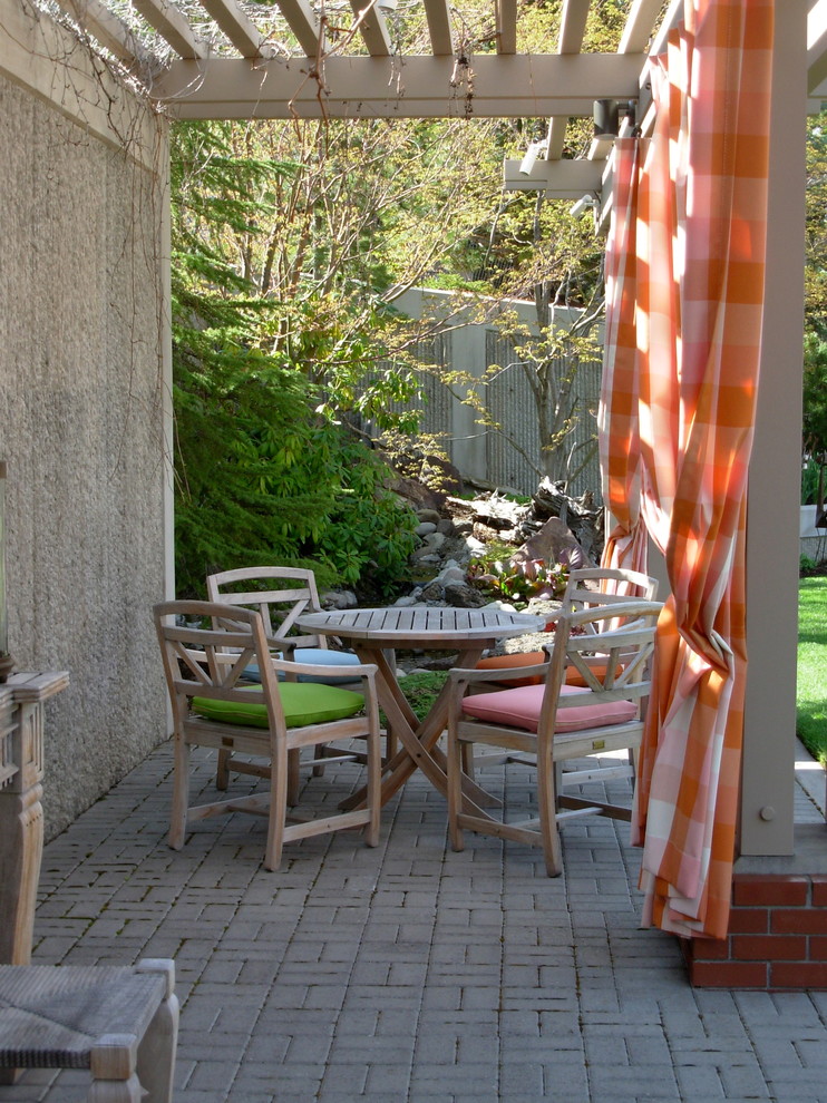 Foto di un ampio patio o portico classico dietro casa con pavimentazioni in mattoni e una pergola