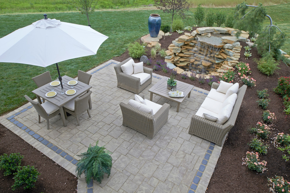 Design ideas for a large traditional back patio in Columbus with a water feature, concrete paving and no cover.