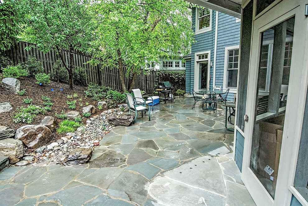 Imagen de patio clásico de tamaño medio en patio trasero con fuente y adoquines de piedra natural