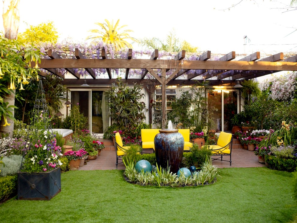 Example of a backyard patio fountain design in Los Angeles with a pergola