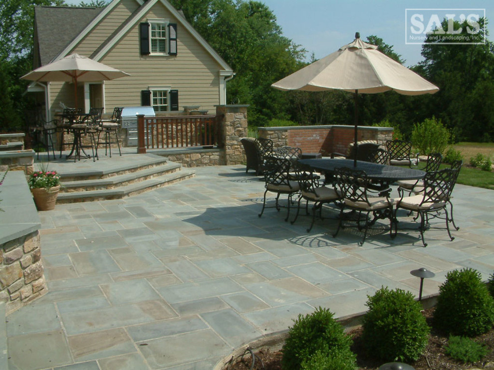 Imagen de patio clásico grande sin cubierta en patio trasero con cocina exterior y adoquines de piedra natural