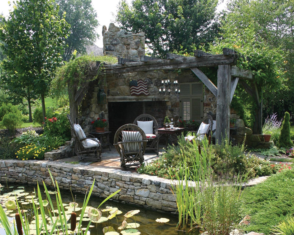 Ejemplo de patio clásico grande en patio trasero con pérgola, fuente y adoquines de piedra natural
