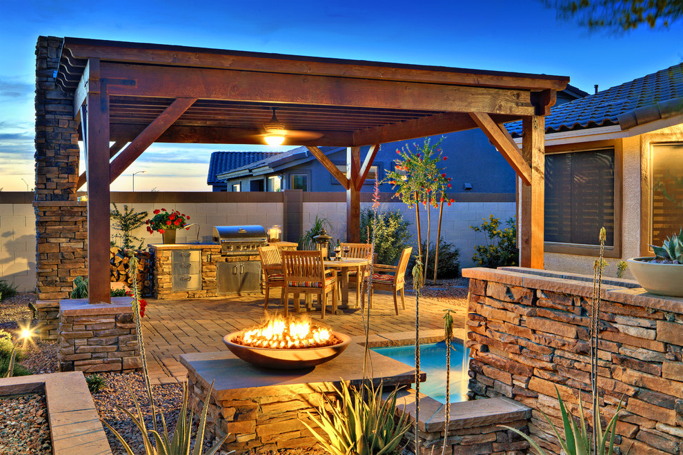 This is an example of a large classic back patio in Phoenix with a fire feature, concrete paving and a pergola.