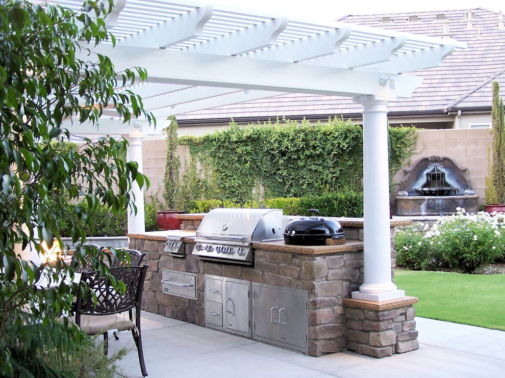 Mittelgroße Mediterrane Pergola hinter dem Haus mit Outdoor-Küche und Betonplatten in Sonstige