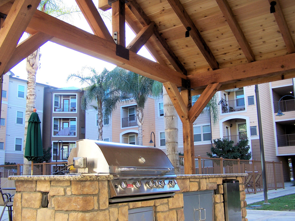 This is an example of a large classic back patio in Other with an outdoor kitchen, concrete slabs and a gazebo.