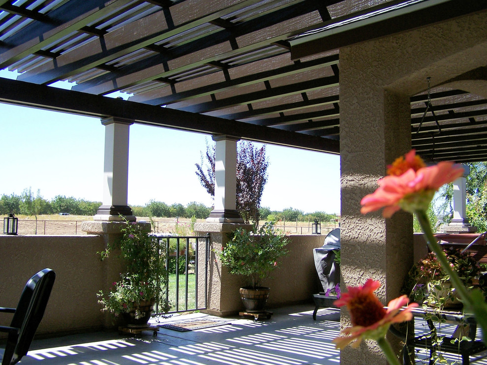 Example of a large tuscan backyard concrete patio design in Other with a roof extension