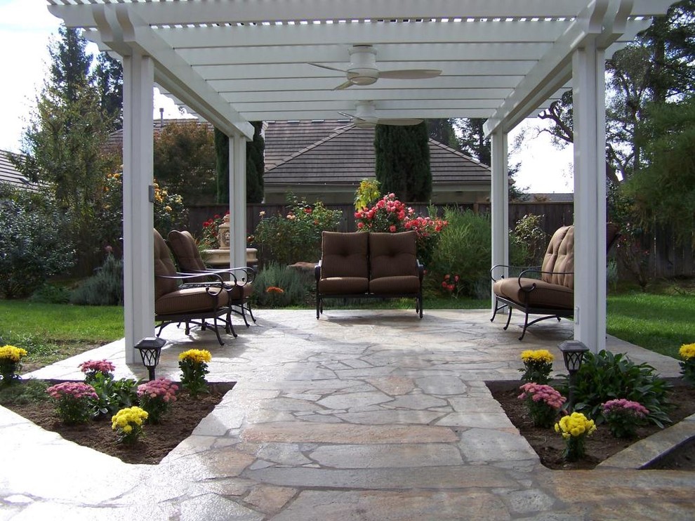 Modelo de patio de estilo americano de tamaño medio en patio trasero con adoquines de piedra natural y pérgola