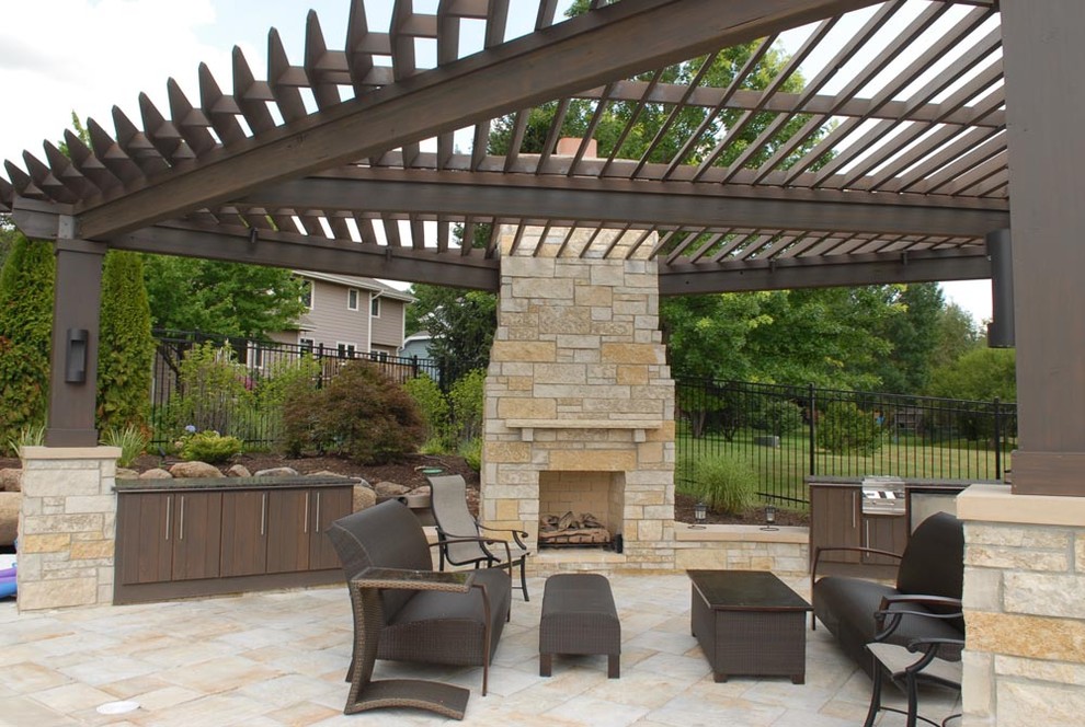 Large classic back patio in Other with a fire feature, natural stone paving and a pergola.