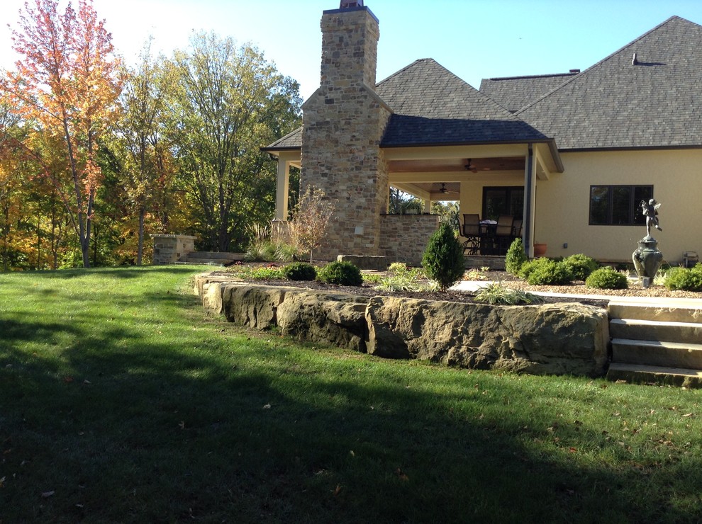 Immagine di un grande patio o portico tradizionale dietro casa con un focolare e pavimentazioni in pietra naturale