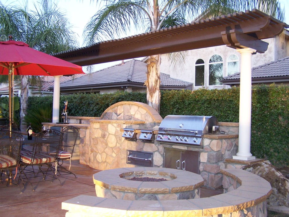 Cette photo montre une terrasse arrière méditerranéenne de taille moyenne avec une cuisine d'été, une dalle de béton et une pergola.