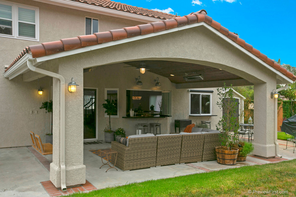 Inspiration pour une grande terrasse arrière traditionnelle avec une dalle de béton et une extension de toiture.