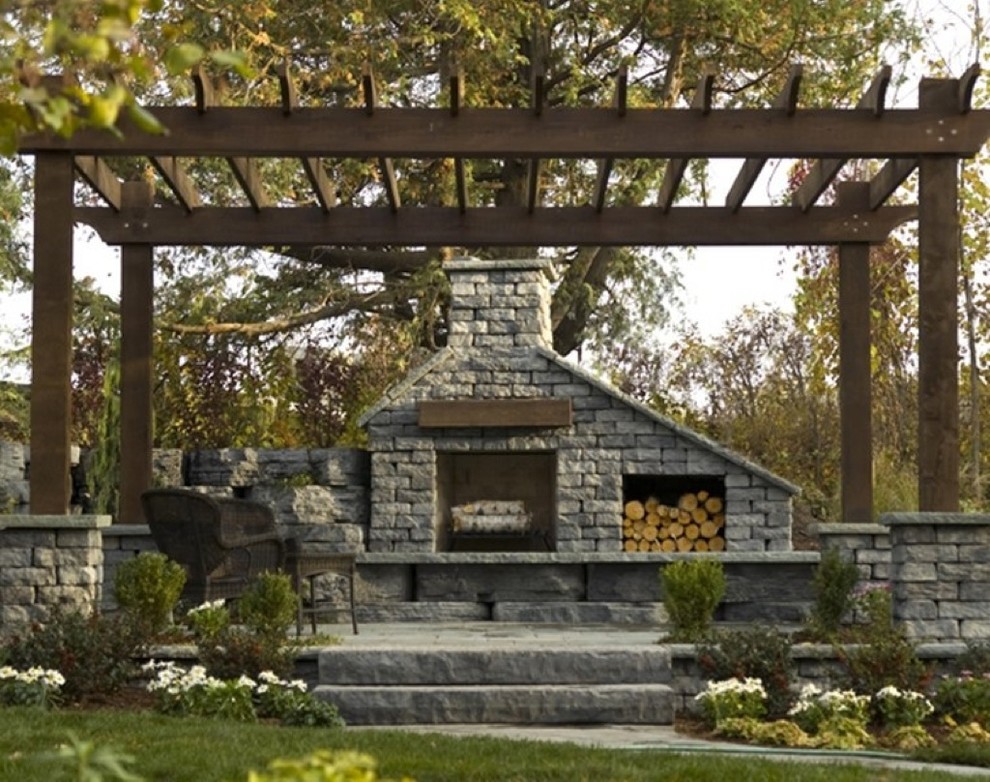 Example of a classic backyard stone patio design in New York with a fire pit