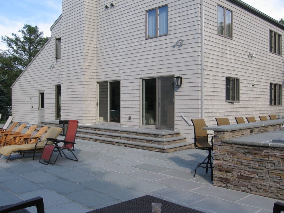 Idées déco pour une grande terrasse arrière classique avec une cuisine d'été et des pavés en pierre naturelle.