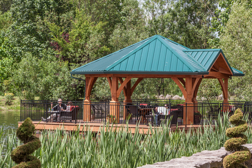 Idee per un grande patio o portico rustico dietro casa con pedane e un gazebo o capanno