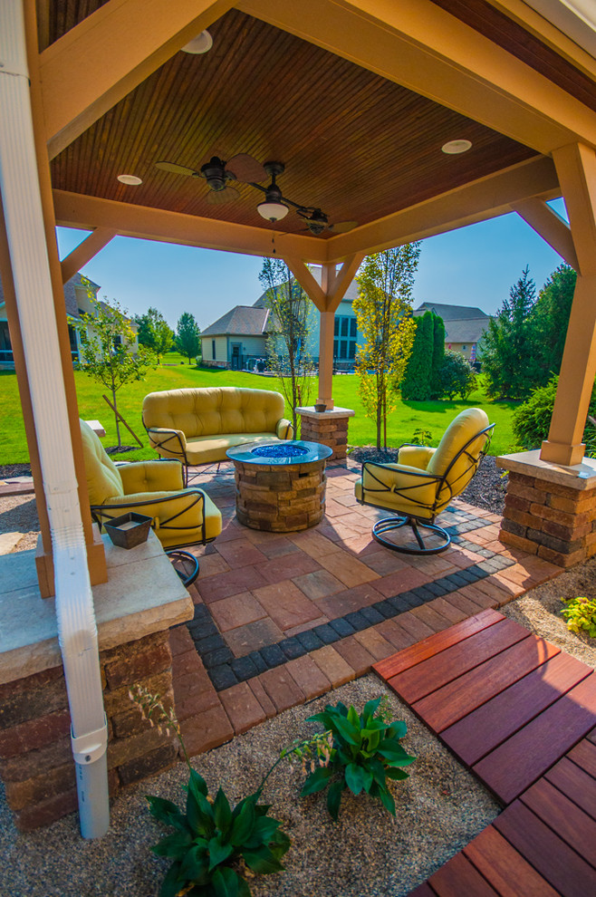 Imagen de patio clásico renovado de tamaño medio en patio trasero con brasero, adoquines de ladrillo y cenador