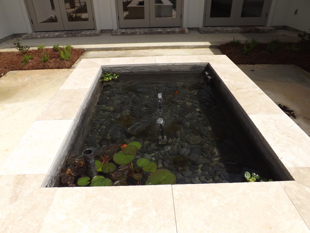 Small world-inspired back patio in New Orleans with a water feature, concrete slabs and no cover.
