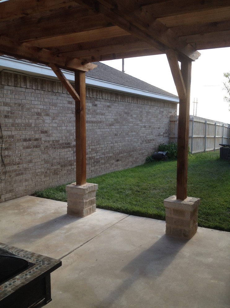Large rustic back patio in Austin with a pergola, a fire feature and concrete paving.
