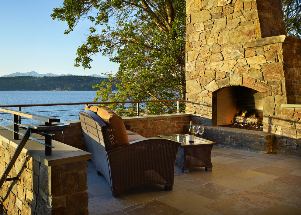 This is an example of a medium sized rustic back patio in Seattle with a fire feature, natural stone paving and no cover.