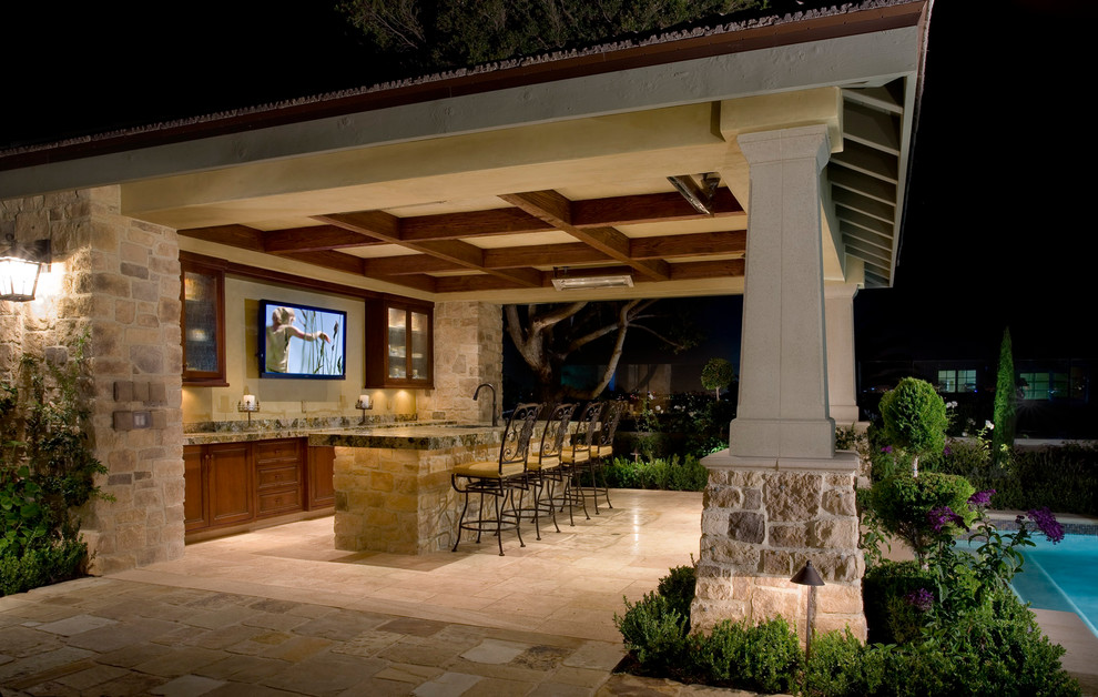 Example of a mid-sized transitional backyard stone patio kitchen design in Orange County with a gazebo