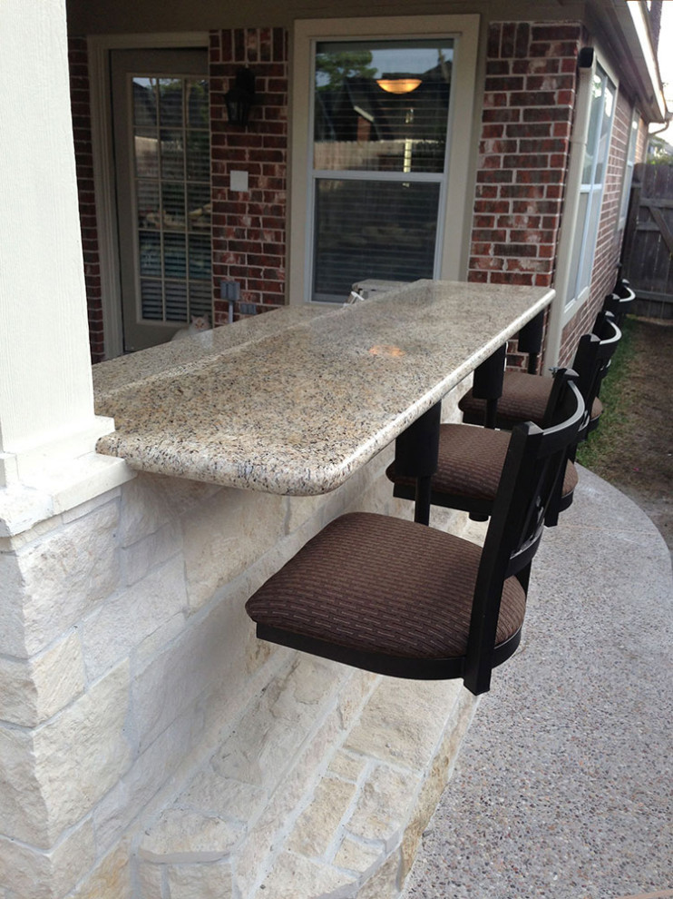 This is an example of a small back patio in Salt Lake City with an outdoor kitchen, natural stone paving and a roof extension.