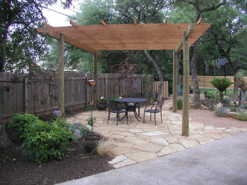 Medium sized mediterranean back patio in Austin with natural stone paving and a pergola.