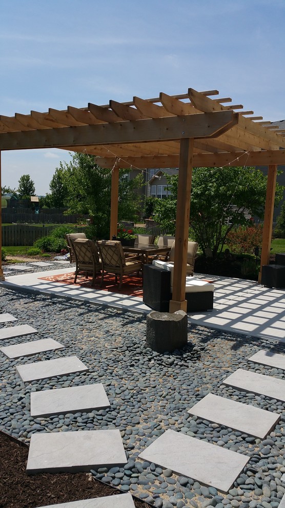 This is an example of a medium sized contemporary back patio in Chicago with a water feature, concrete slabs and a pergola.