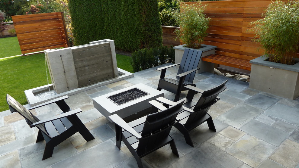 Diseño de patio de estilo americano de tamaño medio sin cubierta en patio trasero con fuente y adoquines de piedra natural