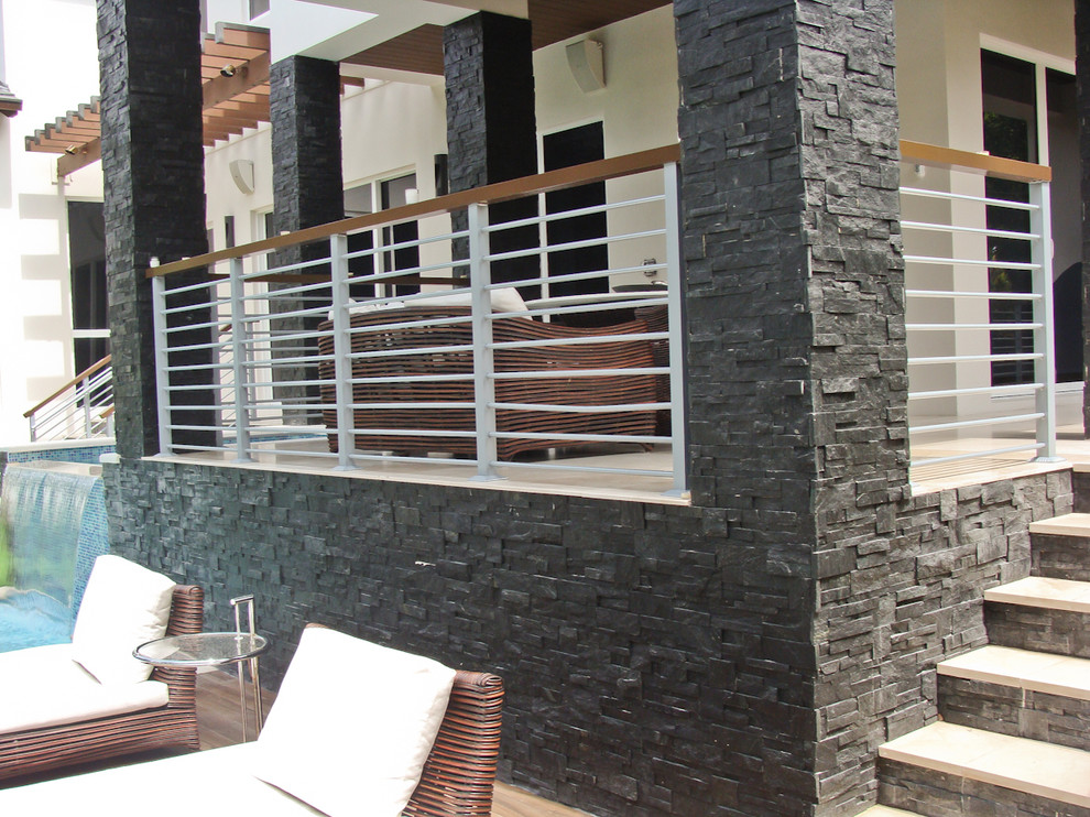 Photo of a contemporary back patio in Miami with natural stone paving and all types of cover.